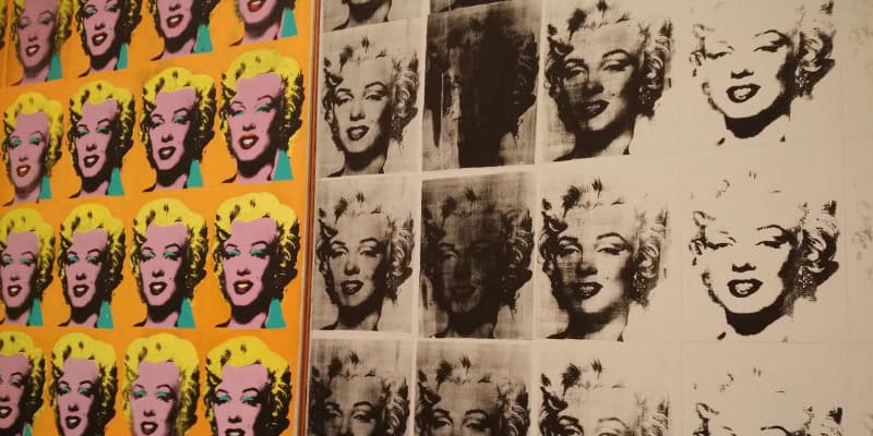 Das Bild zeigt mehrfach wiederholte Porträts von Marilyn Monroe in bunten und schwarz-weißen Farben im Stil der Pop-Art. Die Darstellung erinnert an Andy Warhol und macht Marilyn Monroe zu einer zeitlosen Ikone.