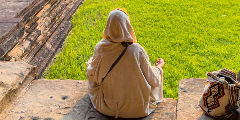 Gott im Alltag - Eine Frau mit dem Rücken zum Berachter im Yogasitz, entspannt und zufrieden
