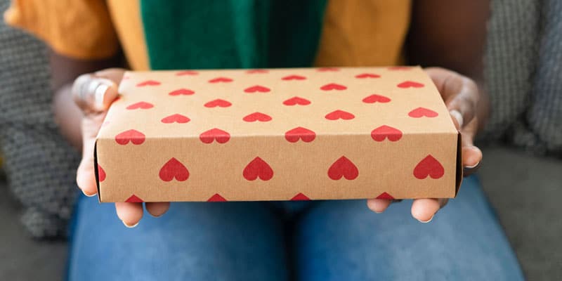 Gott im Alltag - Ein Geschenk, das in Geschenkpapier mit Herzen gewickelt ist als Symbol für großzügiges Verschenken